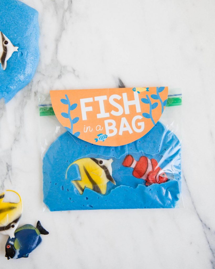 Clever goodie bag favor for a slime party: Seal it up in a baggie and tuck in a few free fish printables from Jamielyn at I Heart Naptime