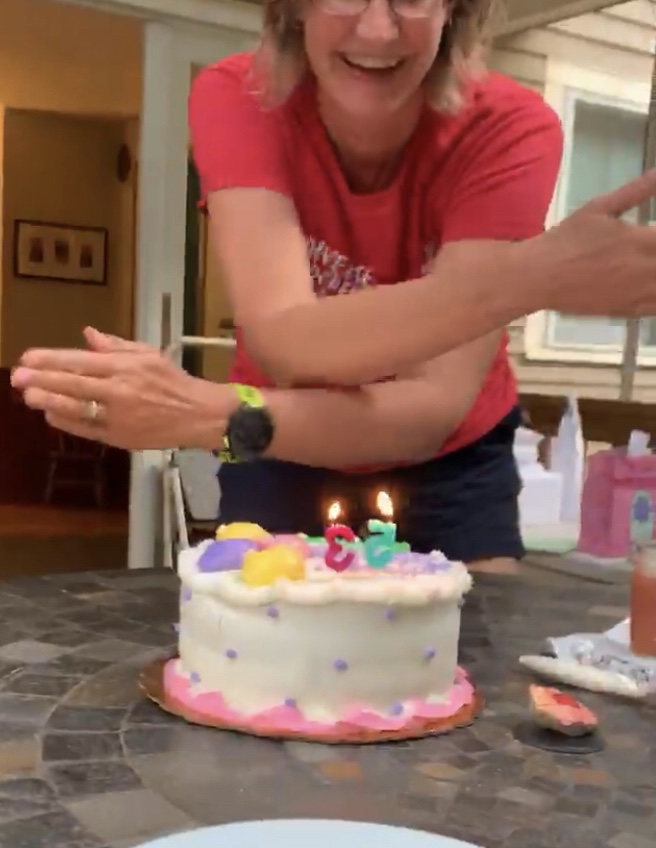 Blowing out candles during Covid pandemic by waving hands over cake