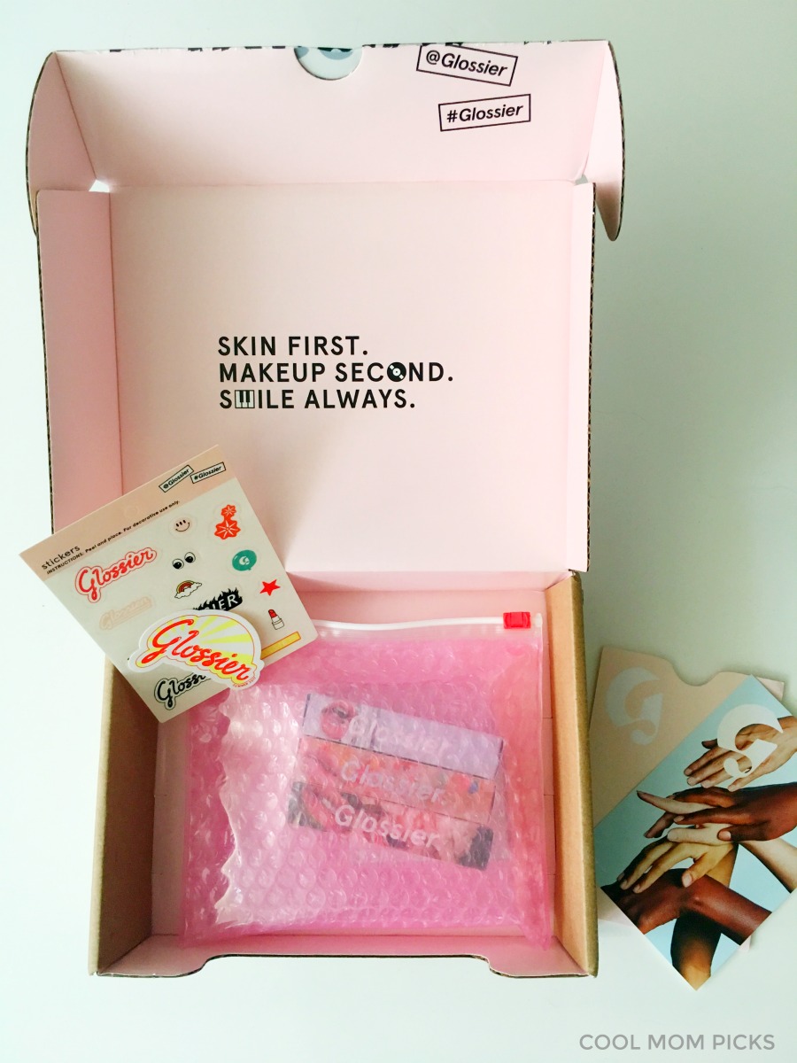Glossier orders come in a fun box with some free samples and stickers, making it a great gift